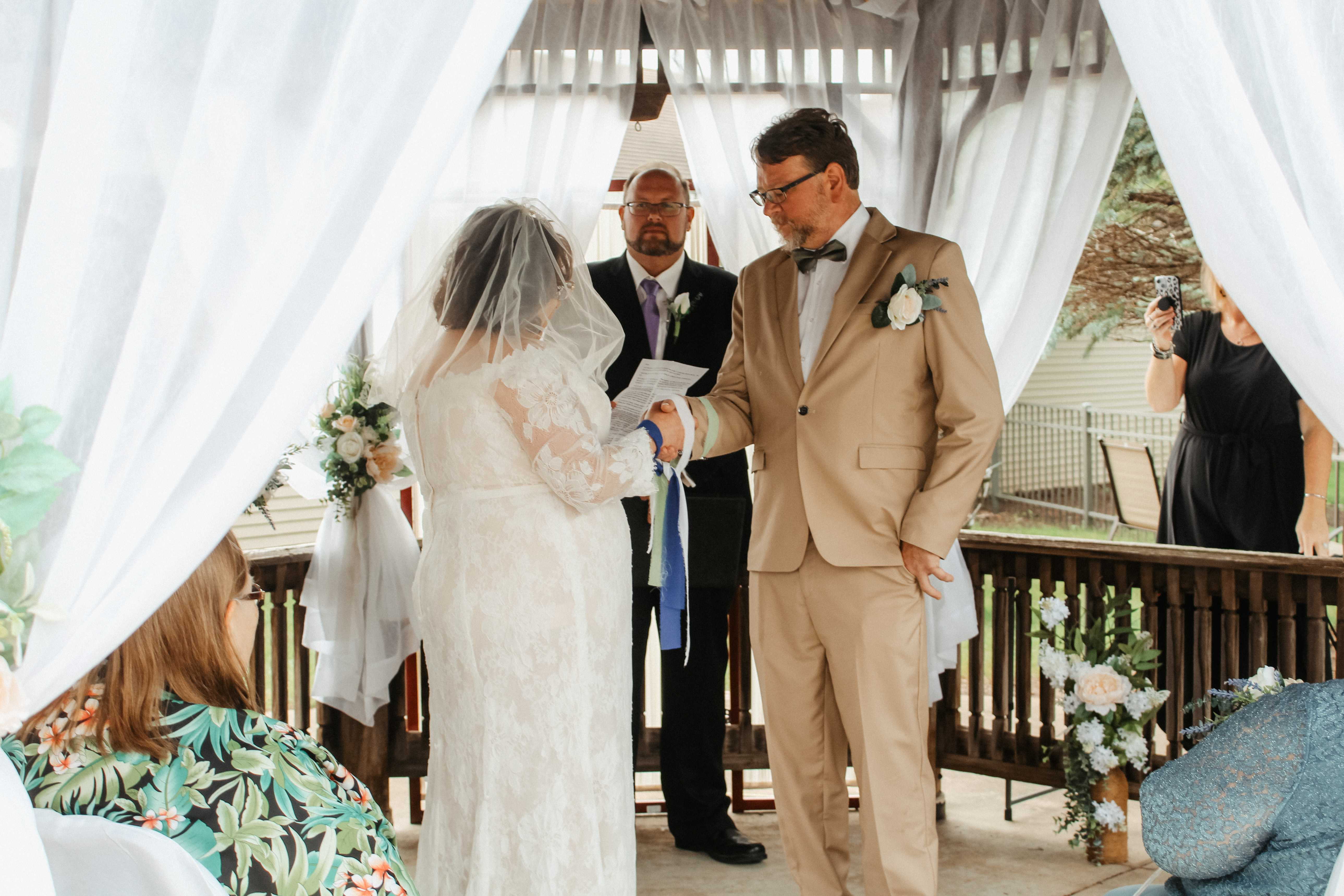 Reading vows during wedding ceremony, bride holding script, handfasted hands
