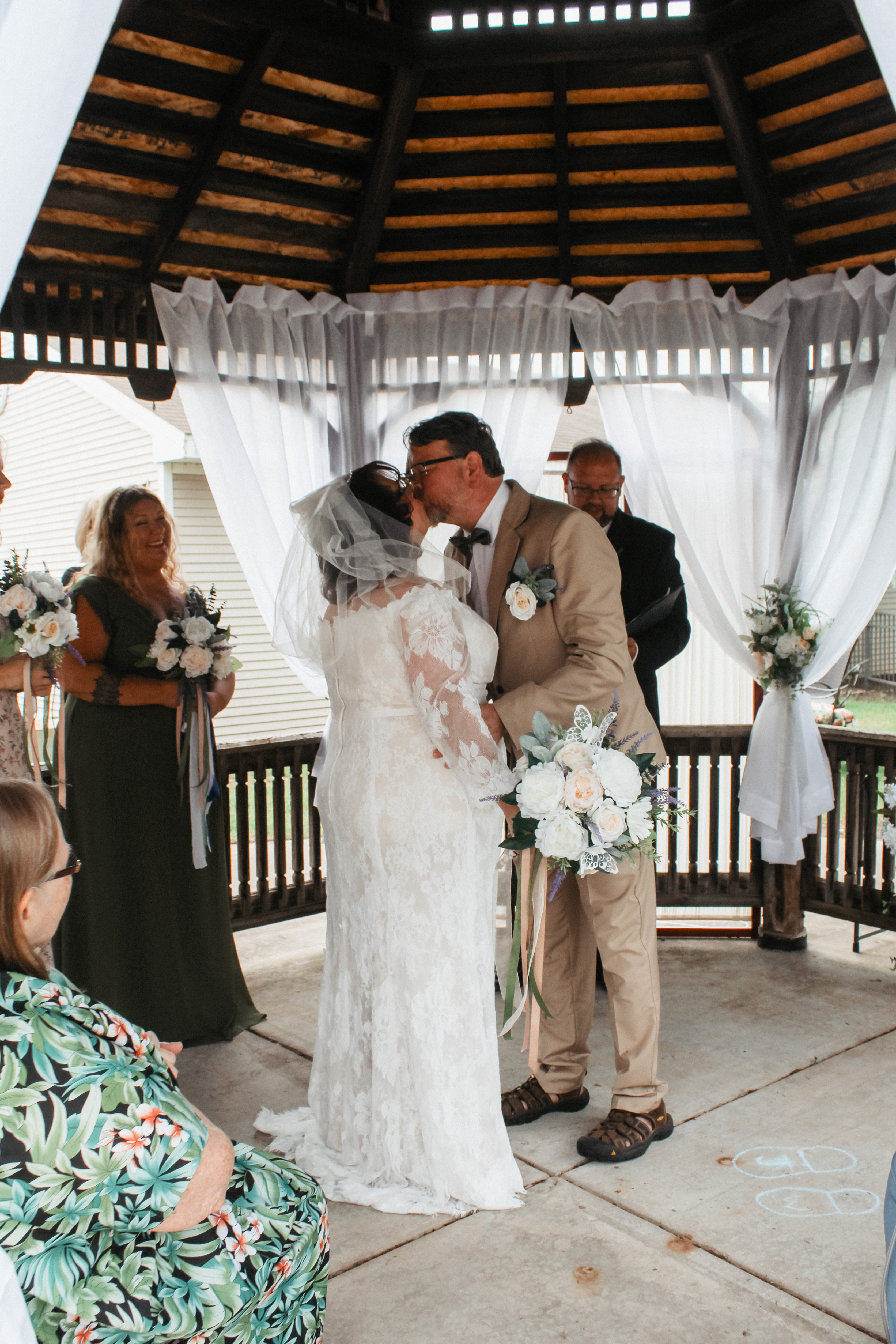 Bride and groom kissing under gazebo, wedding ceremony moment