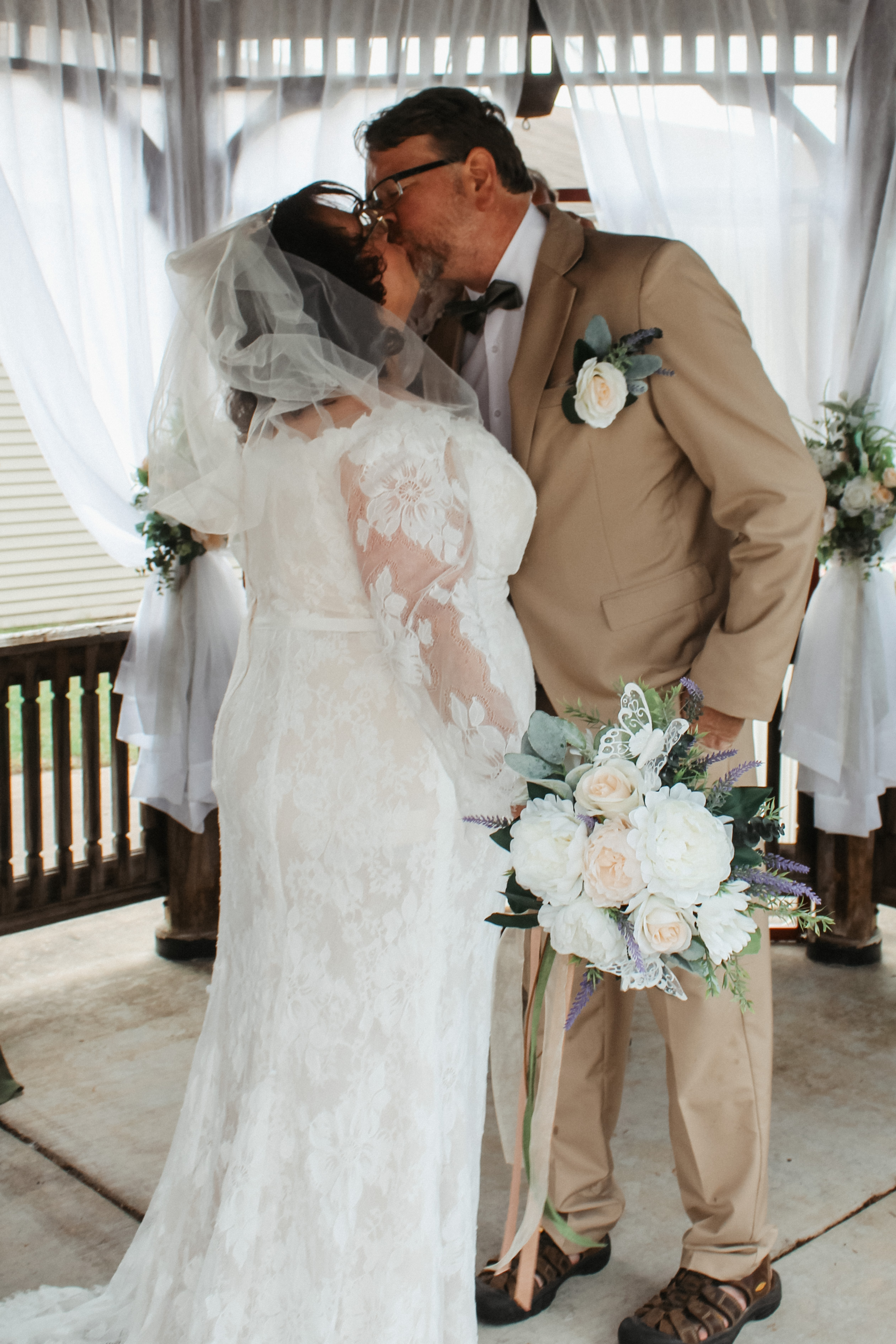 Bride and groom share a kiss, wedding ceremony florals and drapery details