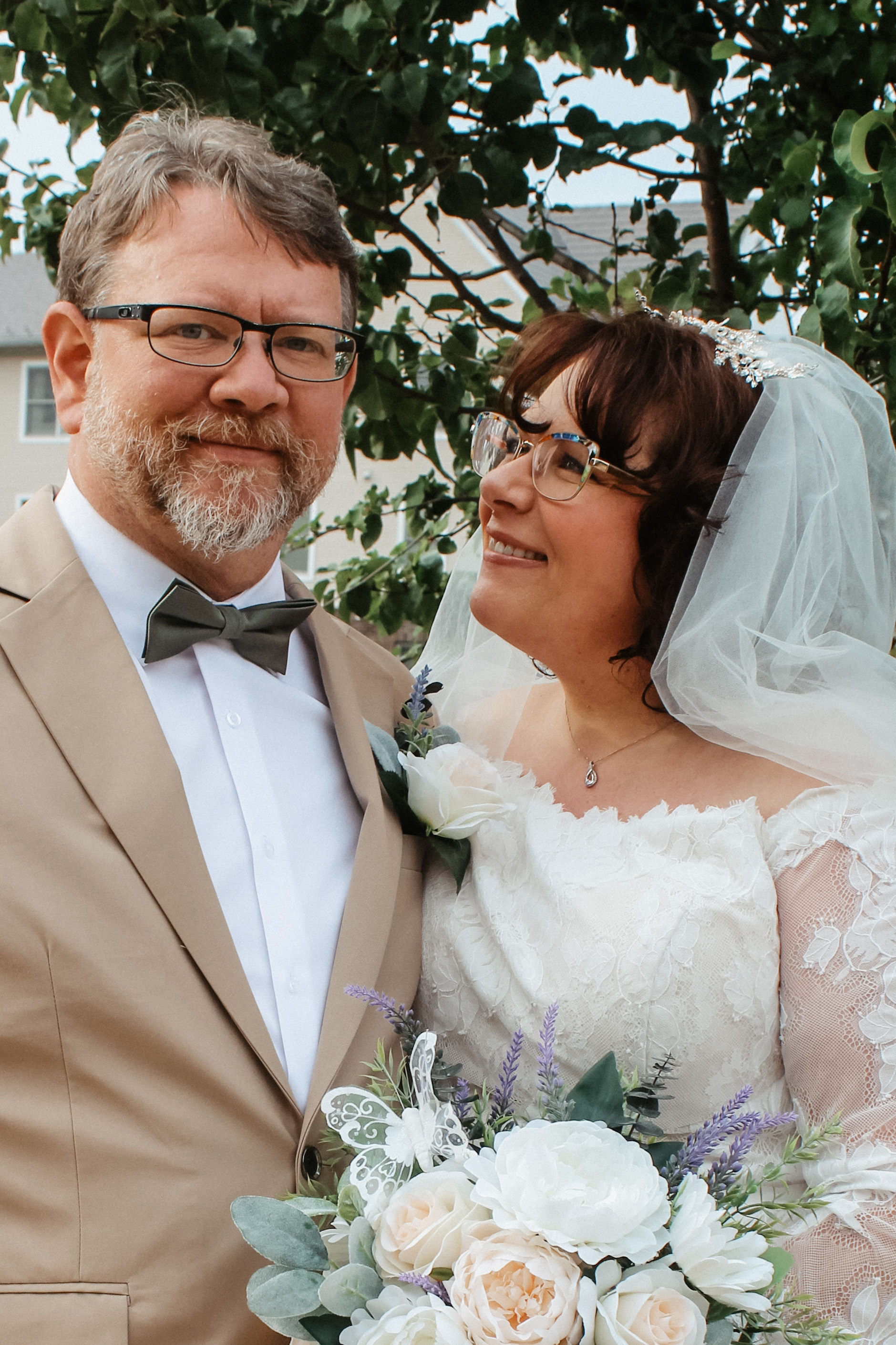 Bride and groom pose outside, bride looking lovingly at groom, wedding portrait