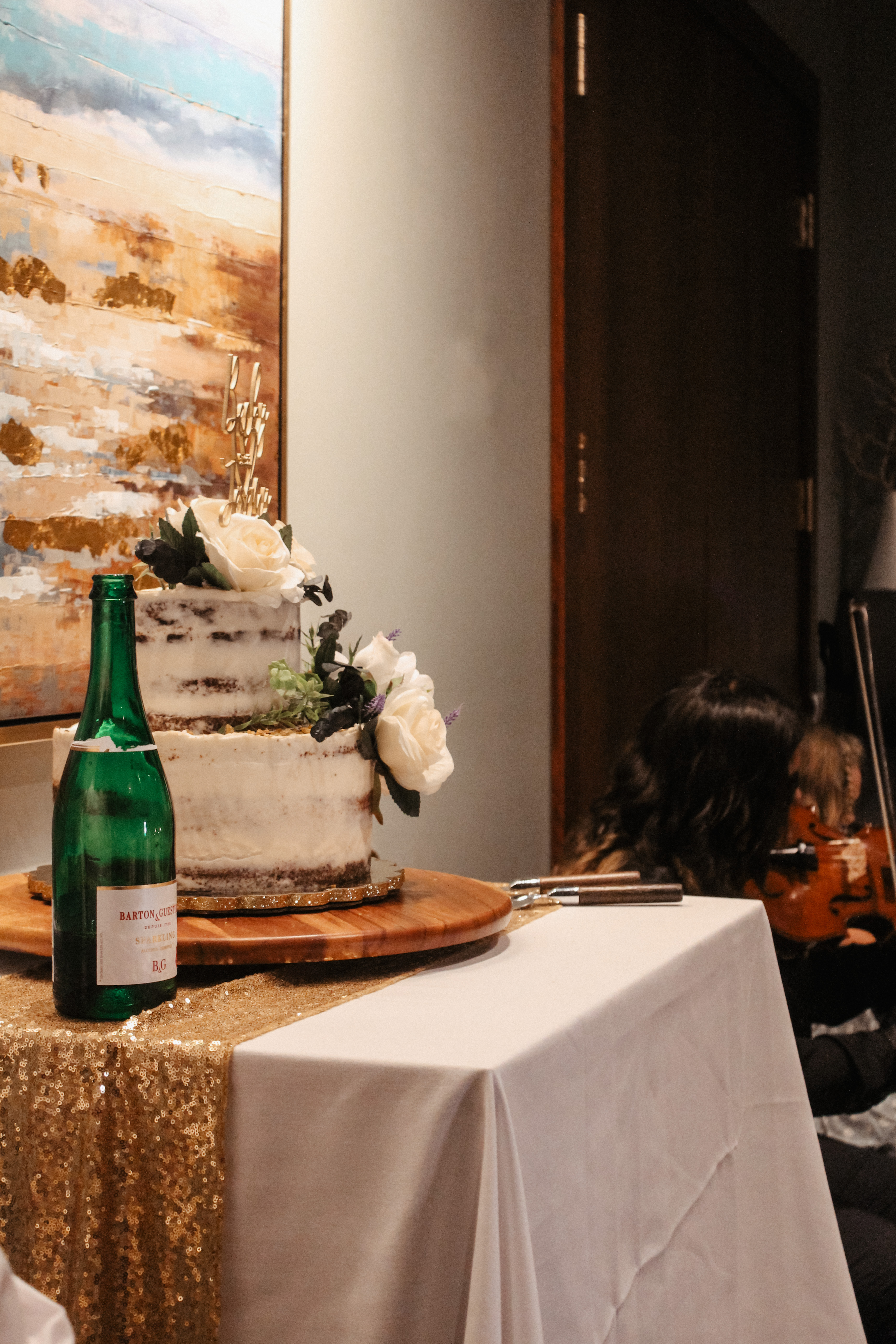 Wedding cake and champagne display with violinist in background, reception detail photo